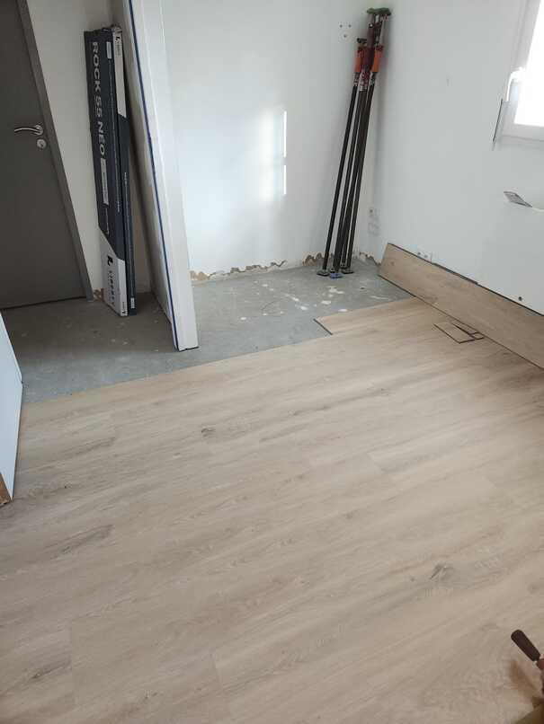 Pose du nouveau revêtement de sol dans une chambre rénovée à Pont-Saint-Martin